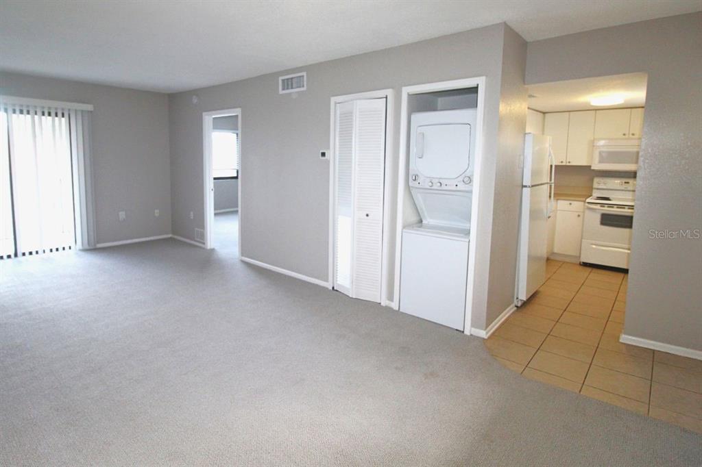 An empty living room with gray carpet, a hanging light fixture, and a sliding glass door — 5310 26TH STREET W UNIT 405, BRADENTON, FL