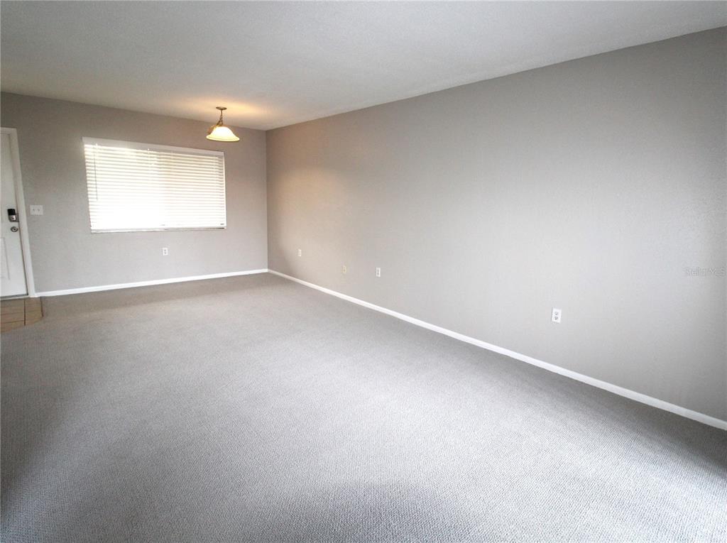 A living room with gray walls, a sectional sofa, a coffee table, and a sliding door — 5310 26TH STREET W UNIT 405, BRADENTON, FL
