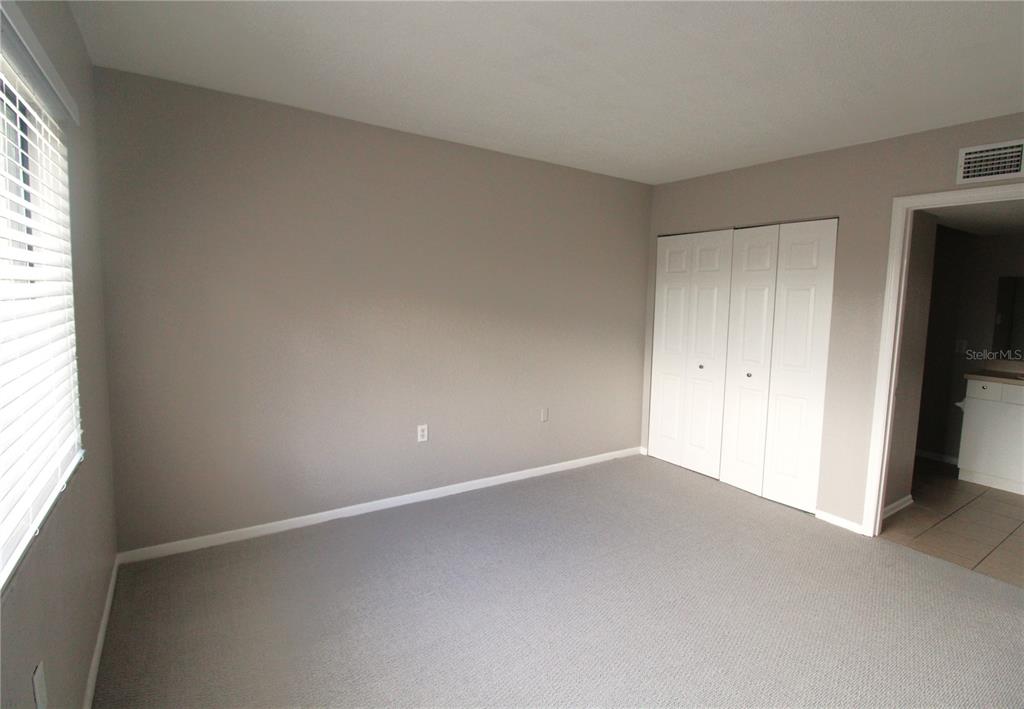 An empty room features gray walls, gray carpeting, a window with blinds, and a pendant light — 5310 26TH STREET W UNIT 405, BRADENTON, FL