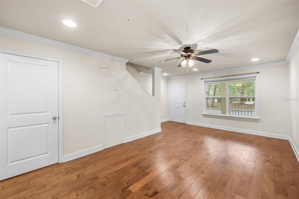 An empty room with hardwood floors, a ceiling fan, and a window overlooking trees — 4605 SW 48TH DRIVE UNIT 155, GAINESVILLE, FL