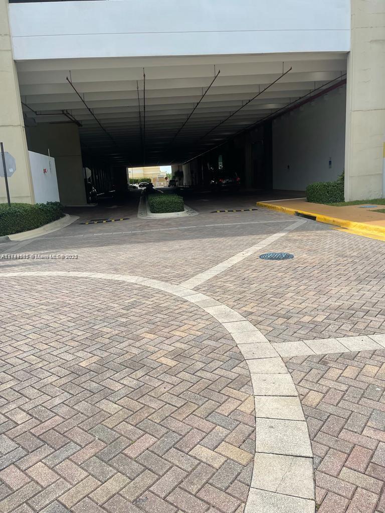 A paved driveway leads into a covered parking garage area with landscaped islands — 1755 E Hallandale Beach Blvd, Hallandale Beach FL 33009, HALLANDALE BEACH, FL