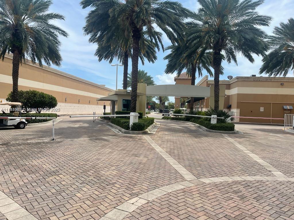 A gated entrance with a guardhouse and palm trees leads to a paved driveway — 1755 E Hallandale Beach Blvd, Hallandale Beach FL 33009, HALLANDALE BEACH, FL