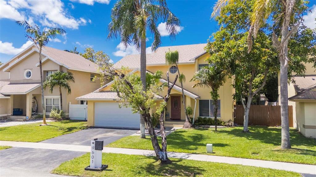 A two-story yellow house with a two-car garage, palm trees, and a front lawn — 9601 SW 9TH COURT, PEMBROKE PINES, FL