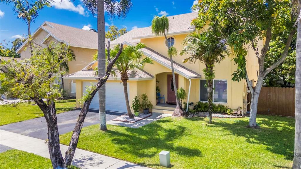 A two-story yellow house with a two-car garage, a front porch, and palm trees — 9601 SW 9TH COURT, PEMBROKE PINES, FL