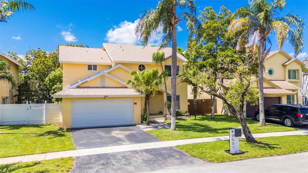 A two-story yellow house with a two-car garage, palm trees, and a front lawn — 9601 SW 9TH COURT, PEMBROKE PINES, FL