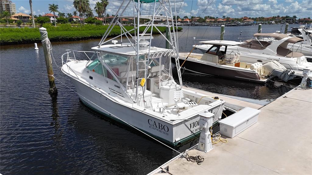 A white Cabo Express sport fishing boat is docked at a concrete pier — 102 RIVIERA DUNES WAY UNIT N-26, PALMETTO, FL