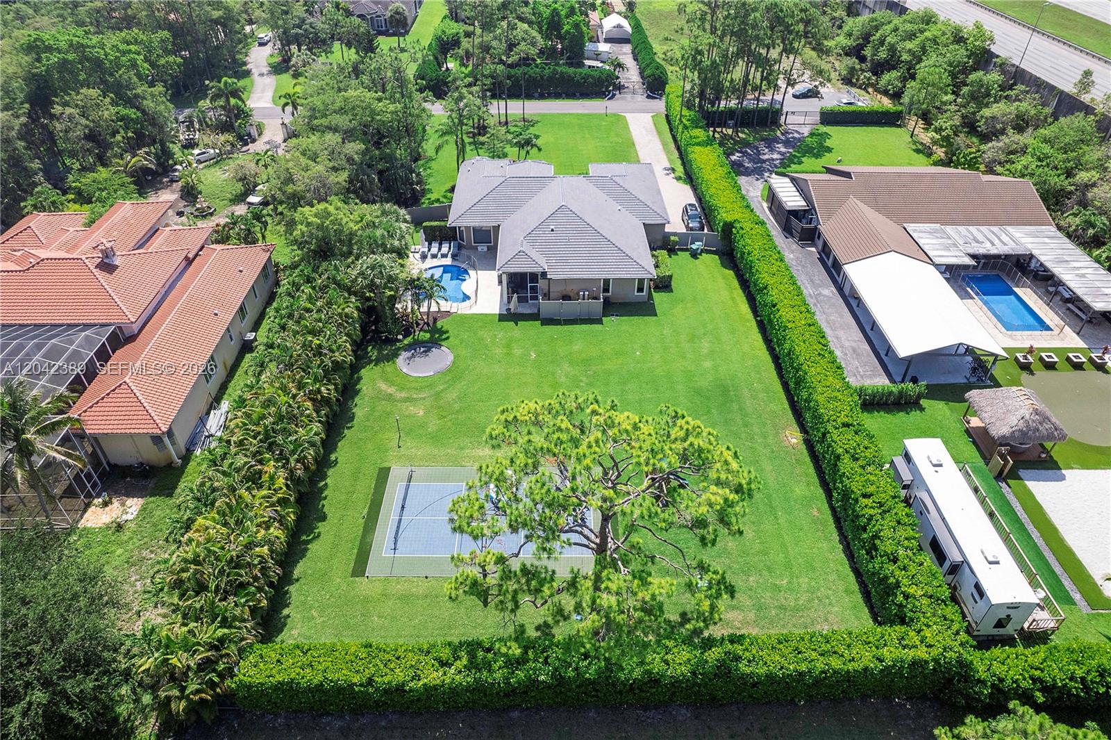 An aerial view shows a house with a pool, tennis court, and large backyard — 5755 NW 72nd Way, Parkland FL 33067, PARKLAND, FL