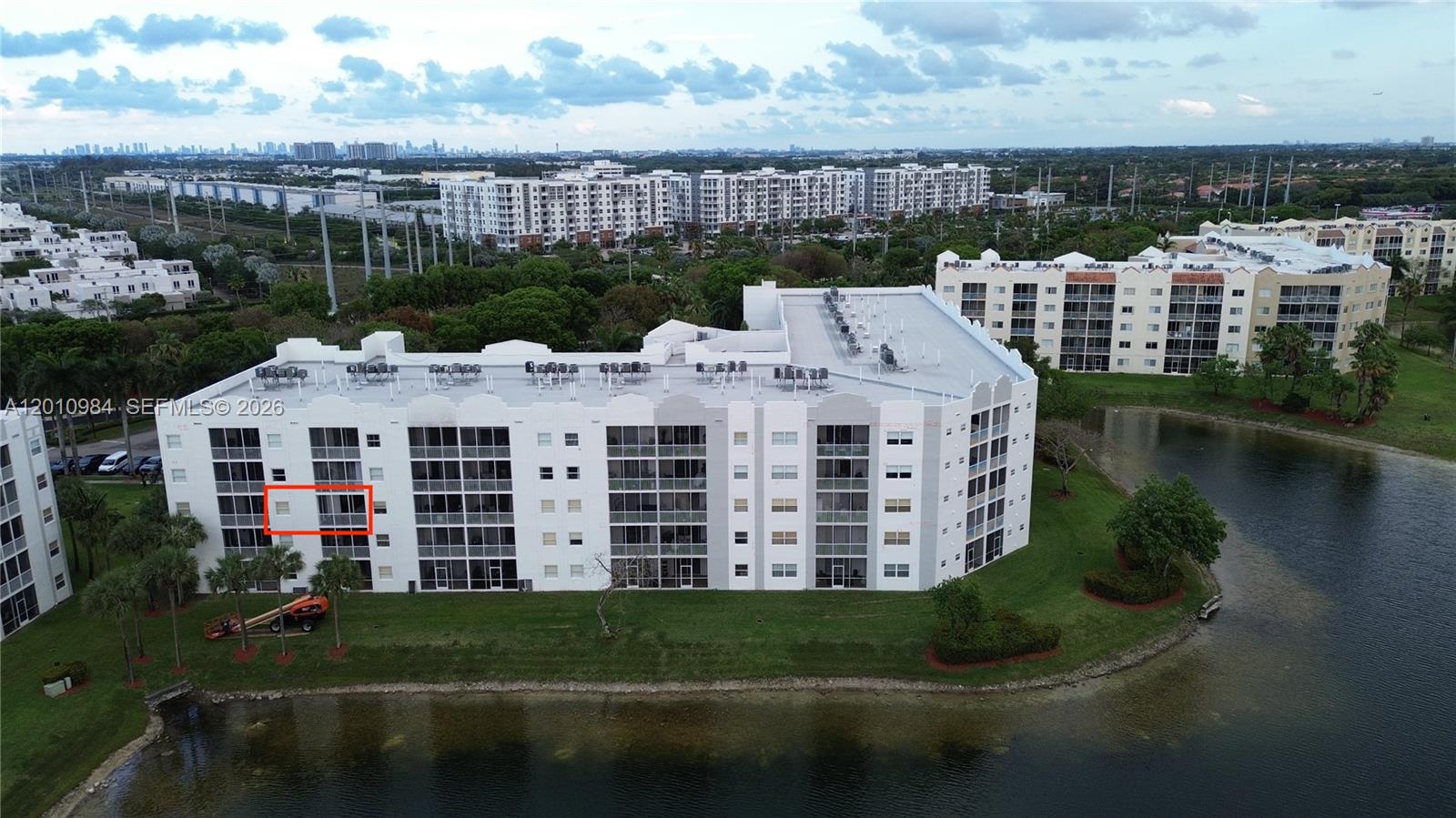 An aerial view shows a multi-story residential building with a red-outlined balcony overlooking a lake — 10730 NW 66th St # 313, Doral FL 33178, DORAL, FL