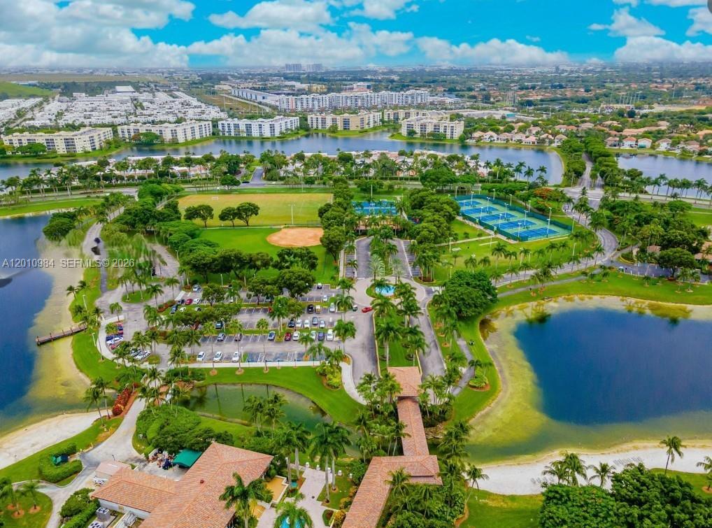 An aerial view shows a community clubhouse with a parking lot, tennis courts, and lakes — 10730 NW 66th St # 313, Doral FL 33178, DORAL, FL