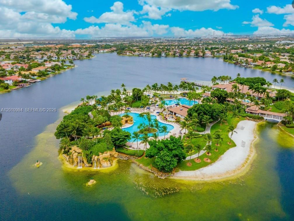 An aerial view of a resort-style island with swimming pools, palm trees, and sandy beaches — 10730 NW 66th St # 313, Doral FL 33178, DORAL, FL