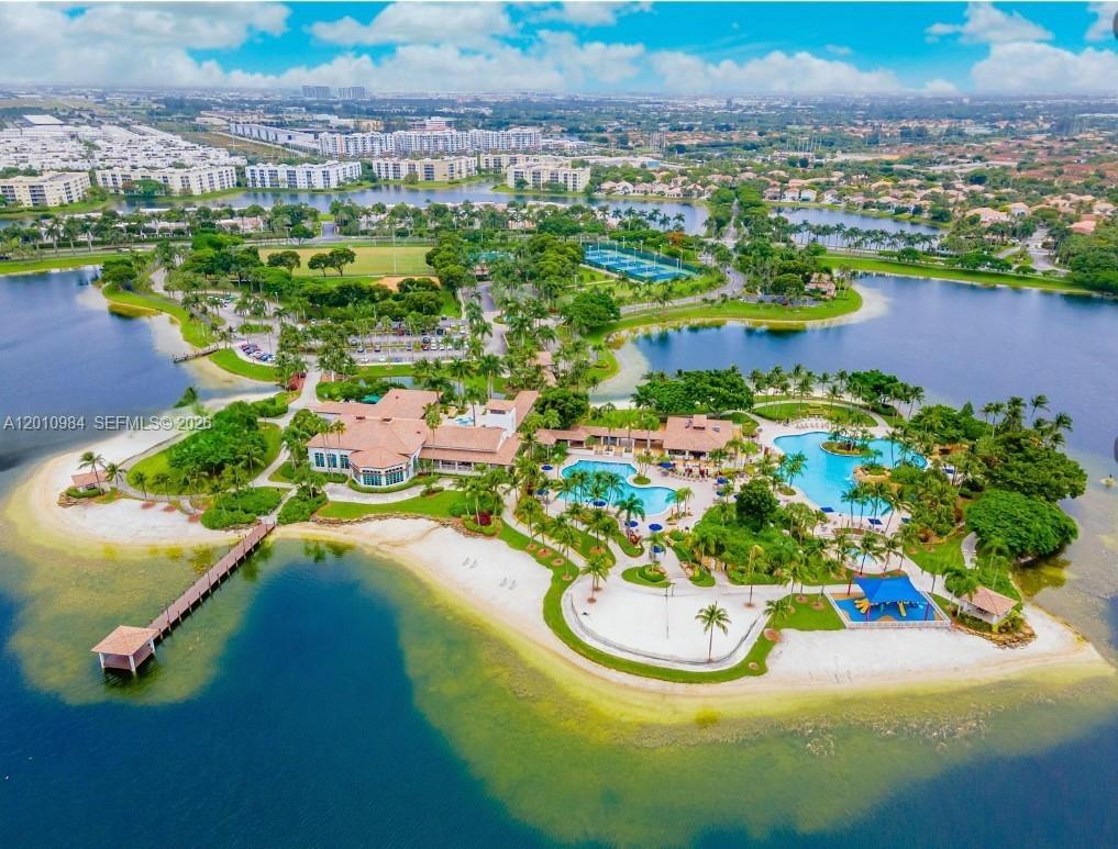 An aerial view shows a clubhouse with swimming pools and a beach on a lake — 10730 NW 66th St # 313, Doral FL 33178, DORAL, FL