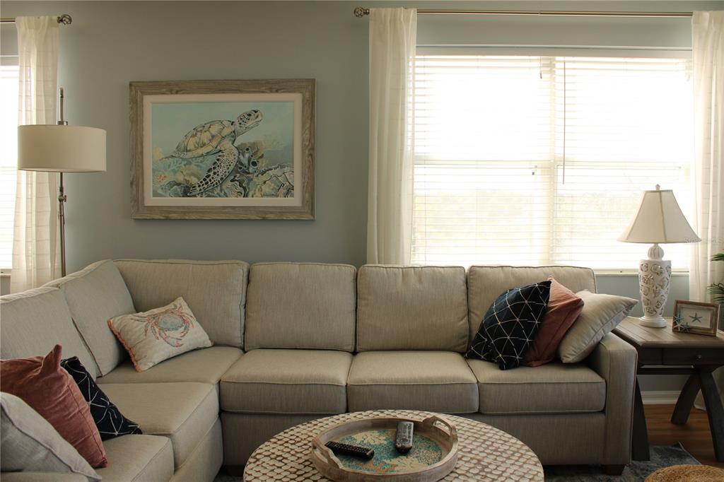 A living room features a beige sectional sofa, a round coffee table, and coastal-themed wall art — 2625 TERRA CEIA BAY BOULEVARD UNIT 401, PALMETTO, FL