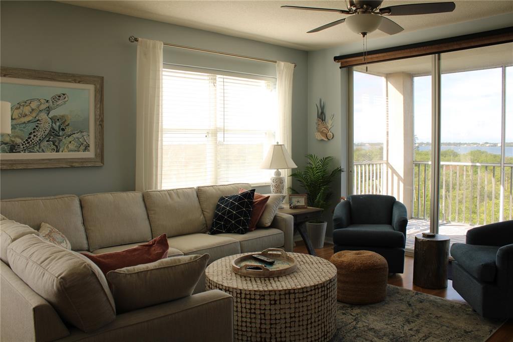 A living room with a sectional sofa, two armchairs, a round coffee table, and balcony access — 2625 TERRA CEIA BAY BOULEVARD UNIT 401, PALMETTO, FL