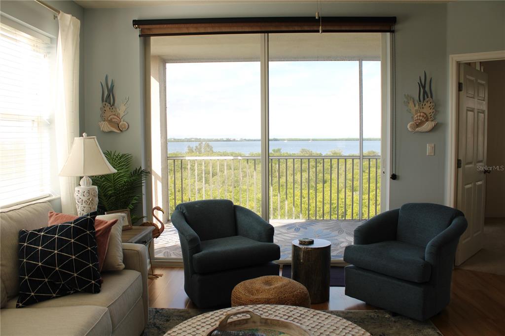 A living room with two blue armchairs, a sofa, and a balcony overlooking the water — 2625 TERRA CEIA BAY BOULEVARD UNIT 401, PALMETTO, FL