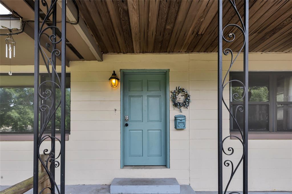 A teal front door with a wreath and mailbox sits between two decorative iron columns — 1474 NE 59TH STREET, OCALA, FL