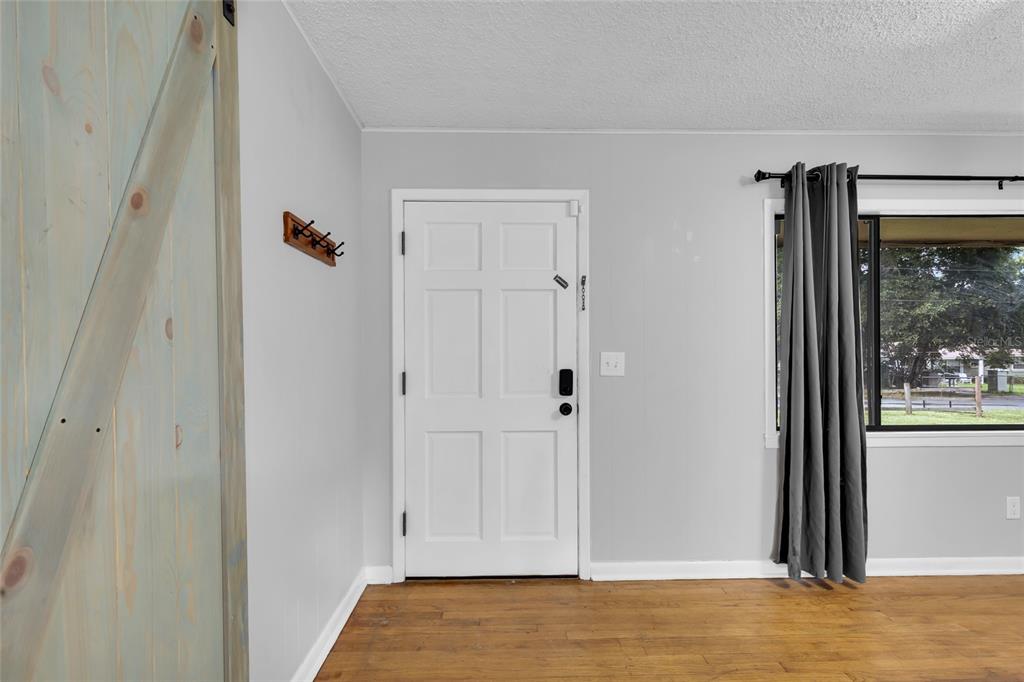 A room with a white front door, a wooden barn door, and a window with curtains — 1474 NE 59TH STREET, OCALA, FL
