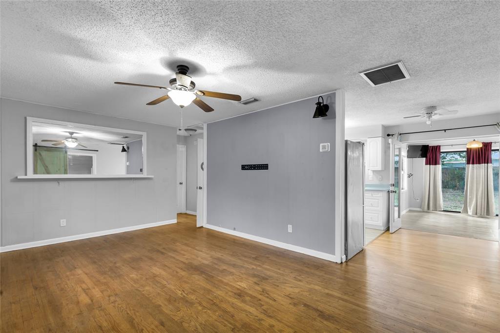 A living room with wood floors, gray walls, a ceiling fan, and an open kitchen — 1474 NE 59TH STREET, OCALA, FL