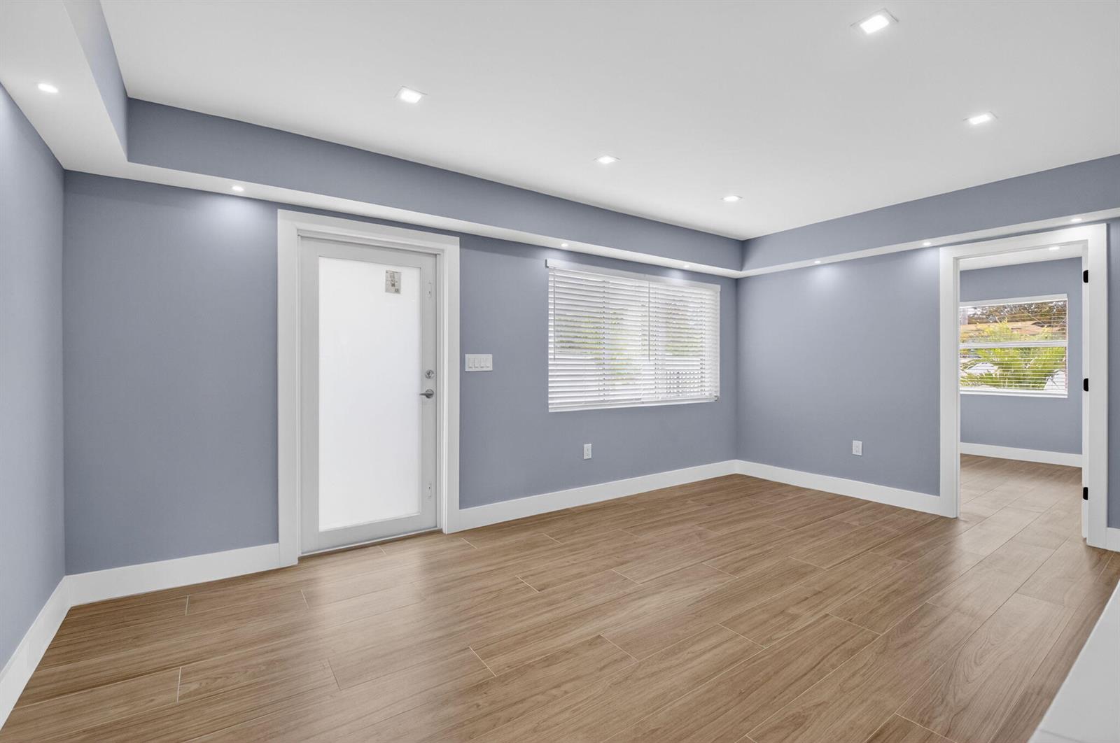 An empty room with blue walls, wood-look tile flooring, recessed lighting, and a glass door — 341 SE 3rd Avenue, Delray Beach FL 33483, DELRAY BEACH, FL