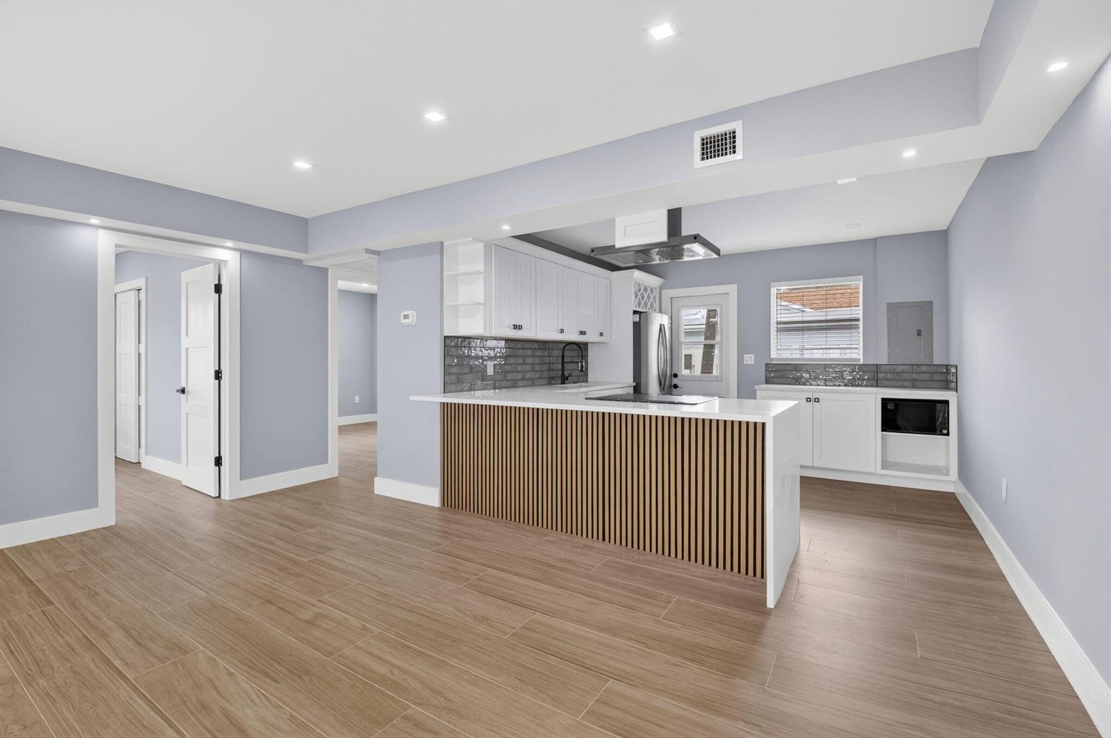 A kitchen features white cabinetry, a wood-slatted island, and light-colored wood-look tile flooring — 341 SE 3rd Avenue, Delray Beach FL 33483, DELRAY BEACH, FL