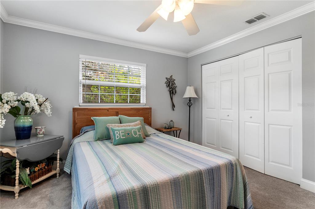 A bedroom features a bed with a striped quilt, a window, and white closet doors — 24 LAKE WOOD CIRCLE, OCALA, FL