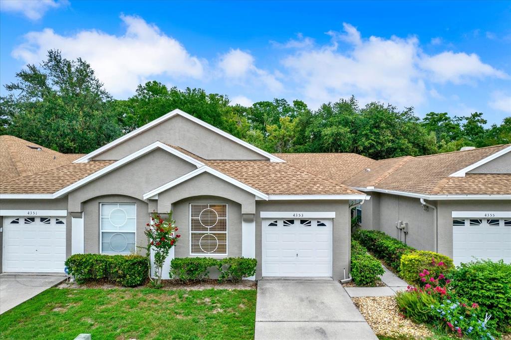 A row of three attached single-story houses with beige stucco siding and brown shingled roofs — 4353 BROOKER CREEK DR, PALM HARBOR, FL