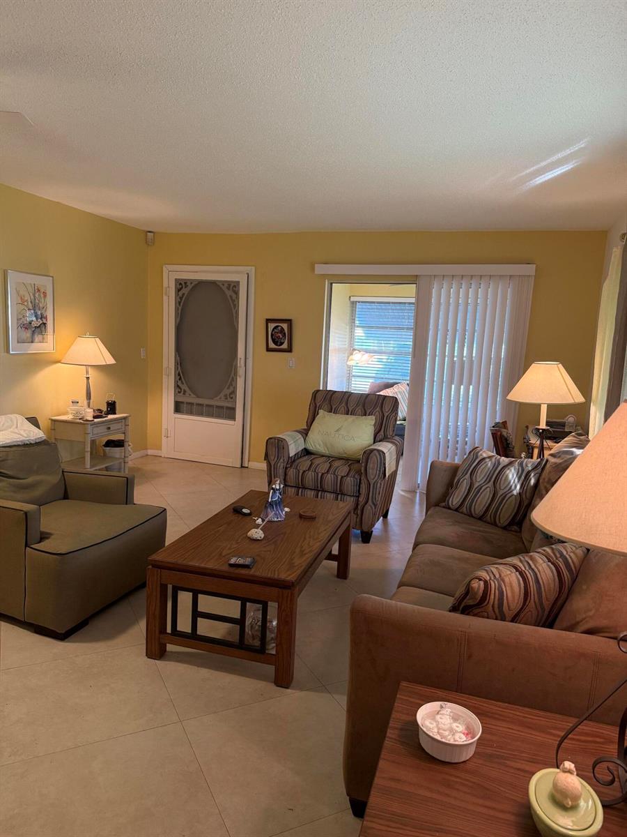 A living room features tile flooring, yellow walls, a sofa, an armchair, and a coffee table — 3311 Valley Road # D, Boynton Beach FL 33435, BOYNTON BEACH, FL