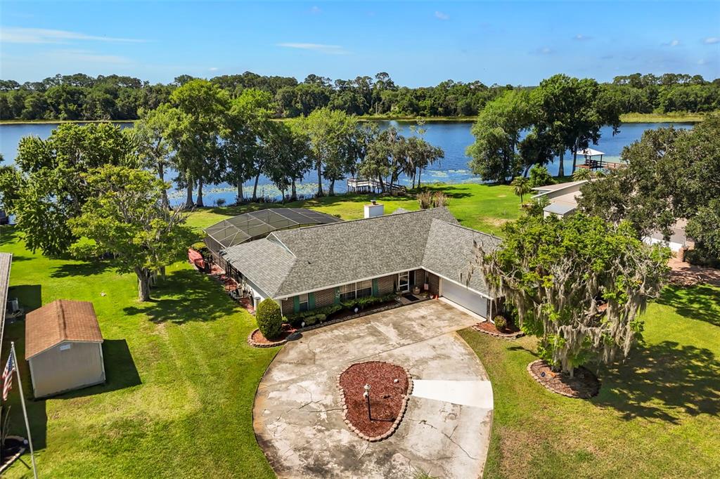An aerial view shows a house with a circular driveway, pool enclosure, and lakefront backyard — 6720 BAY SHORE DRIVE, ST CLOUD, FL