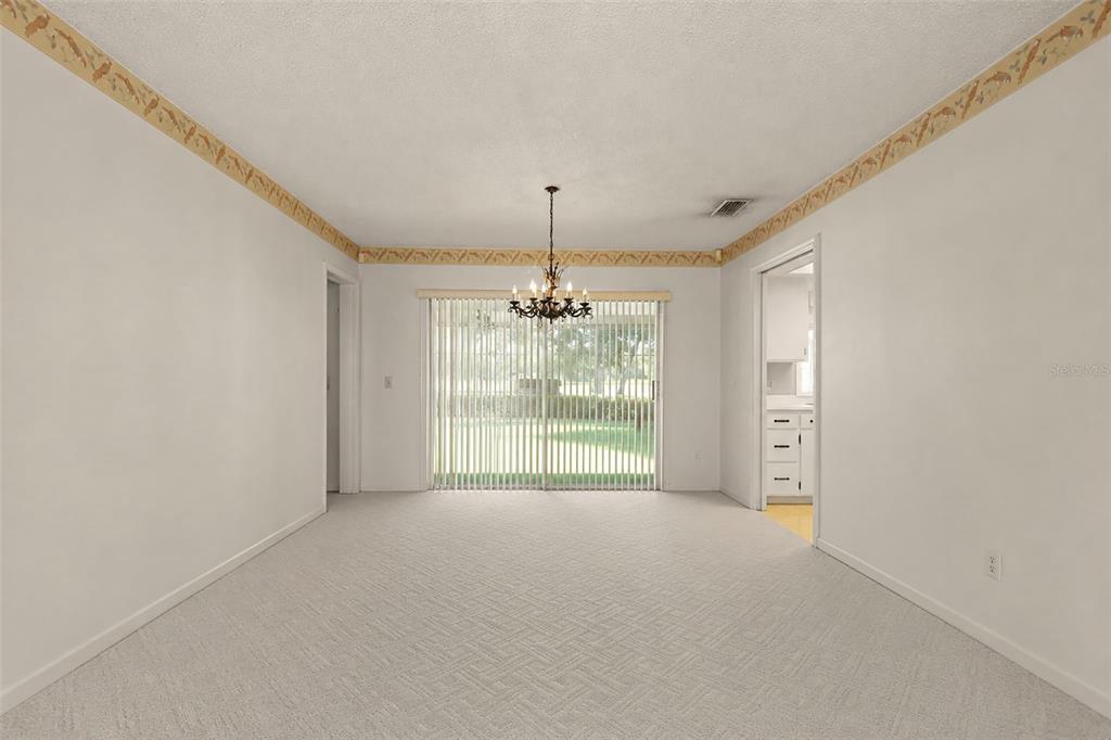 A dining room with white carpet, a chandelier, and sliding glass doors leading outside — 6720 BAY SHORE DRIVE, ST CLOUD, FL