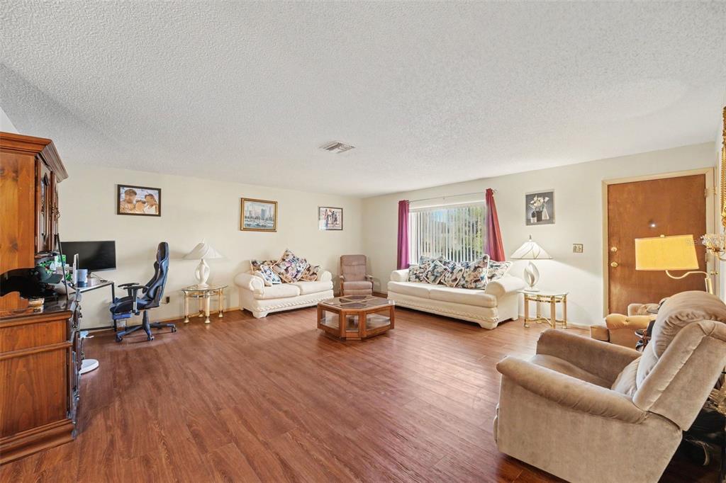 A living room features wood-look flooring, white walls, two sofas, and a desk area — 838 GEORGIA AVENUE, ROCKLEDGE, FL