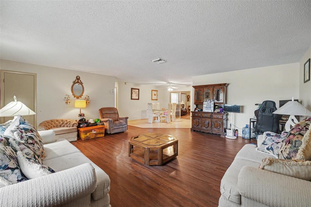 A living room with wood-look flooring, two sofas, a coffee table, and a dining area — 838 GEORGIA AVENUE, ROCKLEDGE, FL