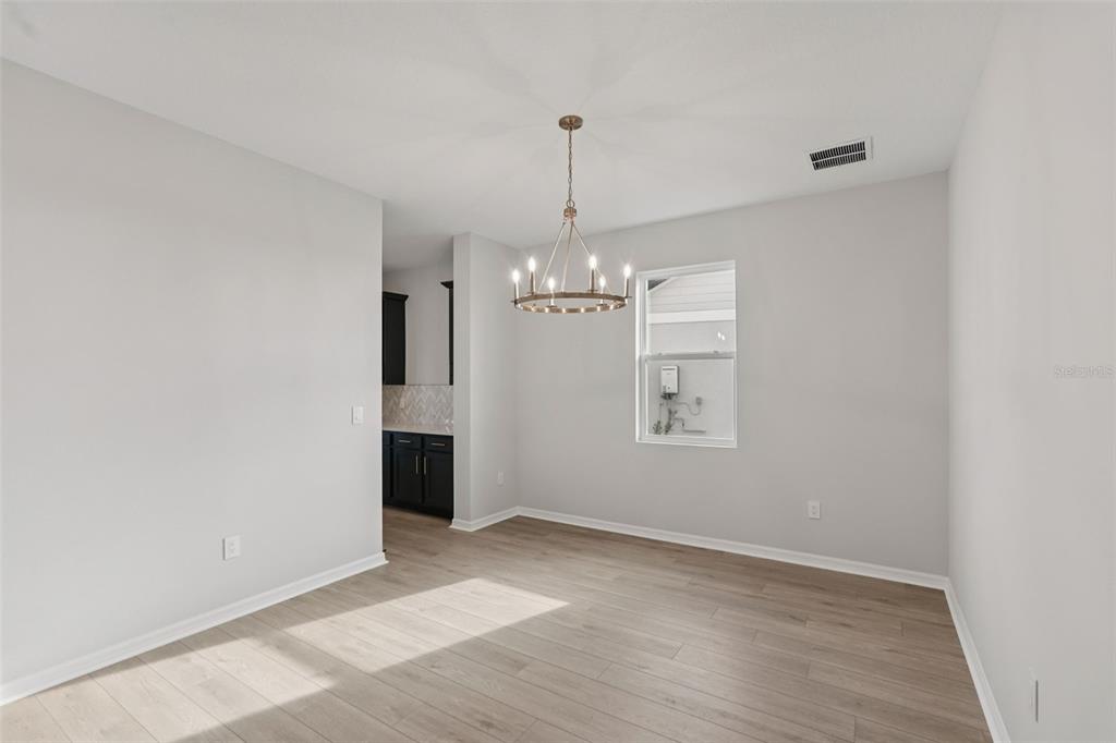 A dining room with light wood-look flooring, a chandelier, and a view into a kitchen — 2902 CITRUS GROVE STREET, WIMAUMA, FL