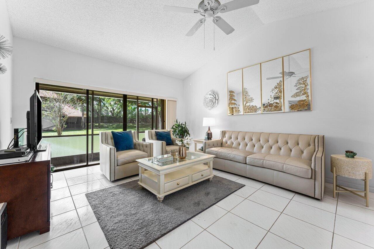A living room features a tufted sofa, two armchairs, a coffee table, and sliding glass doors — 10 Via De Casas Sur # 104, Boynton Beach FL 33426, BOYNTON BEACH, FL
