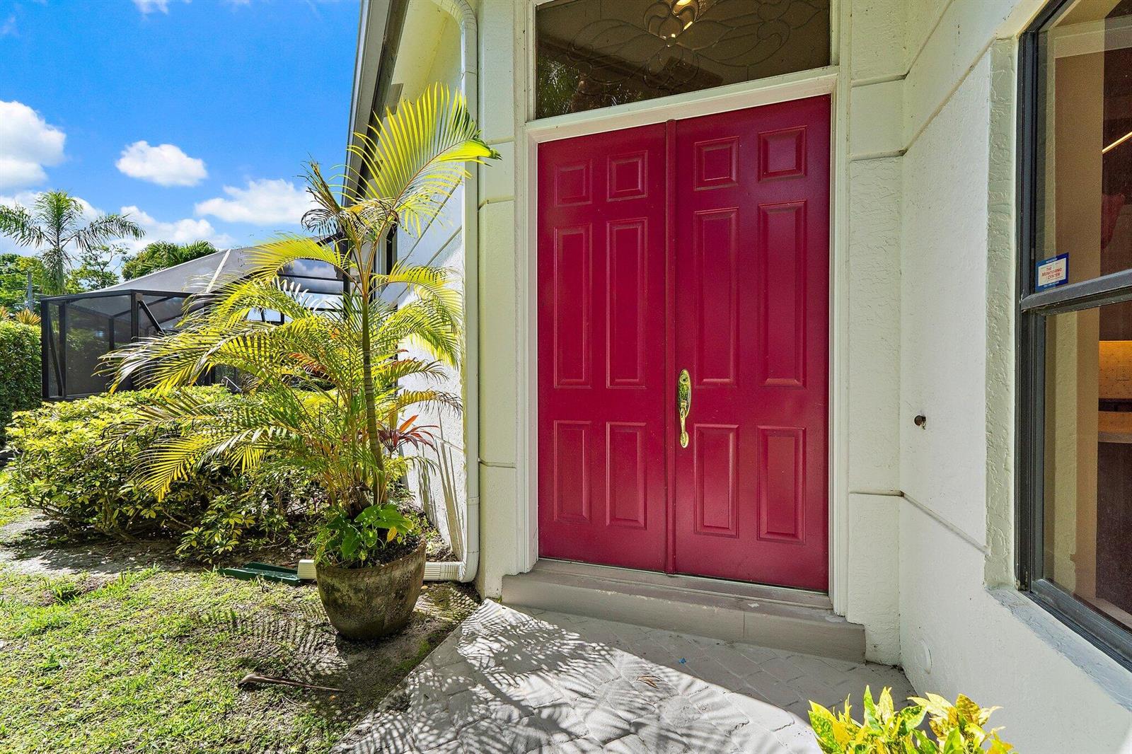 A bright red double front door stands at the entrance of a white stucco home — 1106 Sand Drift Way # A, West Palm Beach FL 33411, WEST PALM BEACH, FL
