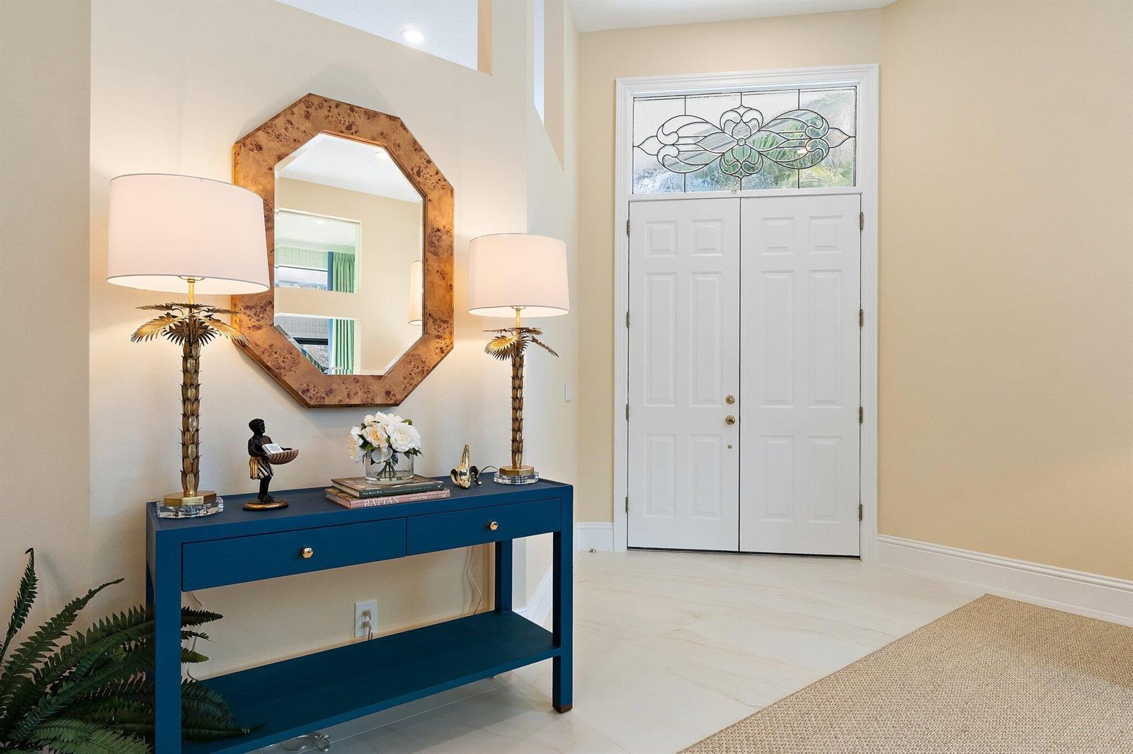A blue console table with two lamps and a mirror sits in a bright entryway — 1106 Sand Drift Way # A, West Palm Beach FL 33411, WEST PALM BEACH, FL