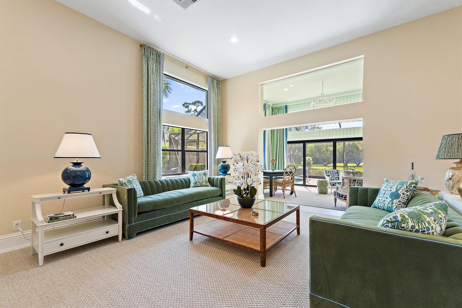 A living room features two green velvet sofas, a glass coffee table, and tall windows — 1106 Sand Drift Way # A, West Palm Beach FL 33411, WEST PALM BEACH, FL