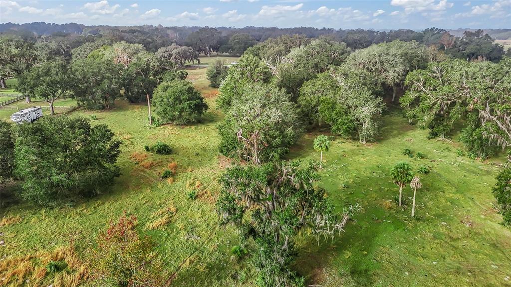An aerial view shows a grassy field with scattered trees and a parked recreational vehicle — TRACT 1 - CR 221, WILDWOOD, FL