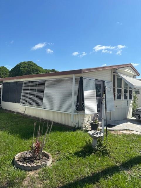 A single-story mobile home with horizontal siding, metal window awnings, and a small front yard — 9000 US HWY 192 UNIT 381, CLERMONT, FL