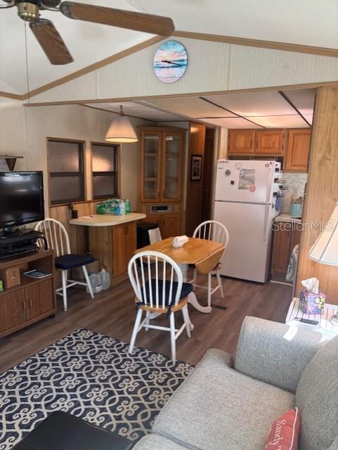 A living room and dining area with wood-paneled walls, a ceiling fan, and light flooring — 9000 US HWY 192 UNIT 381, CLERMONT, FL