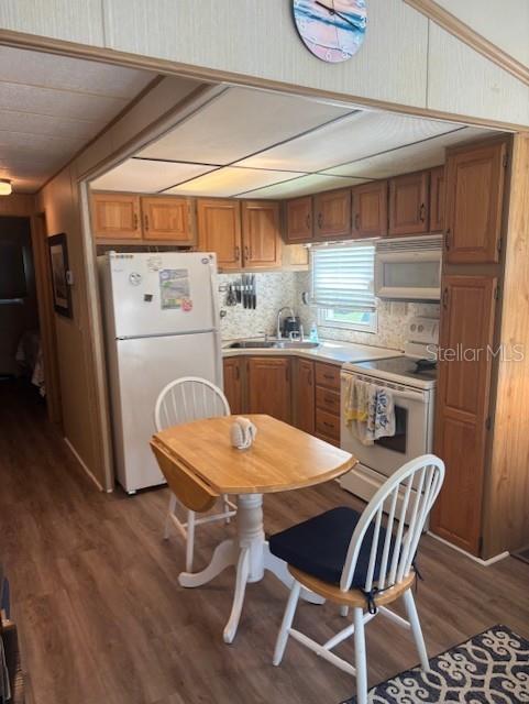 A kitchen features wood cabinets, white appliances, a small dining table, and wood-look flooring — 9000 US HWY 192 UNIT 381, CLERMONT, FL