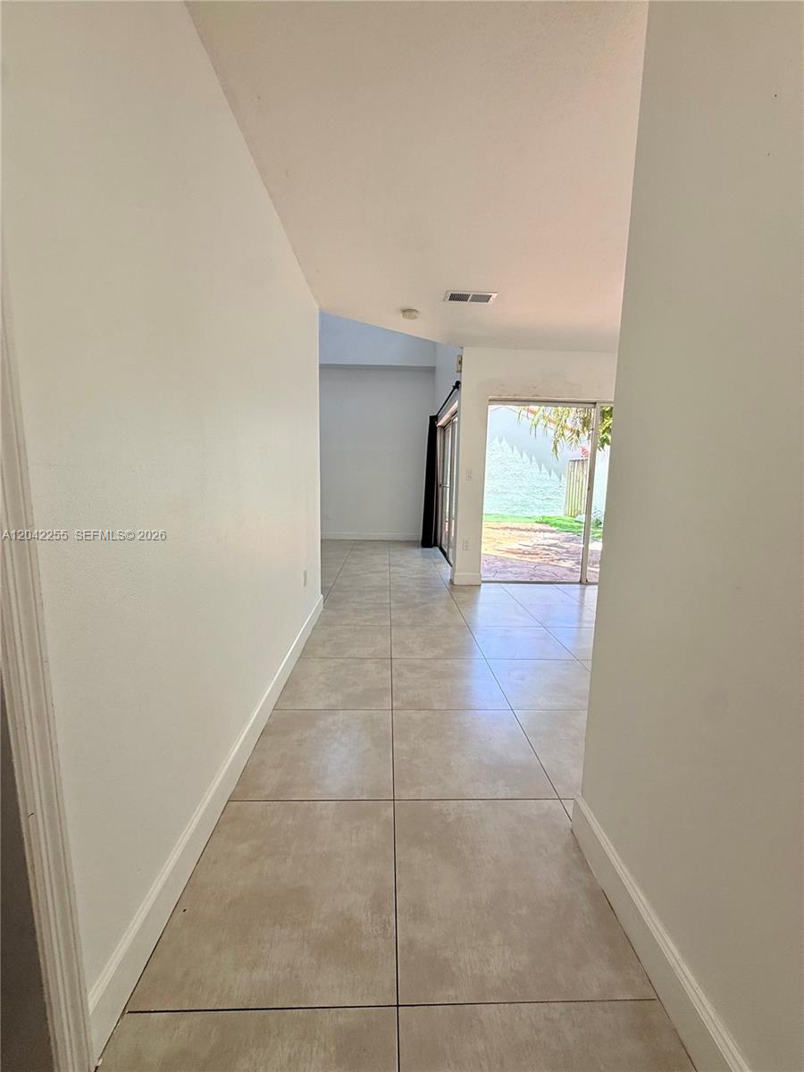 A tiled hallway leads to a living area with sliding glass doors opening to a patio — 14912 SW 104th St # 48, Miami FL 33196, MIAMI, FL