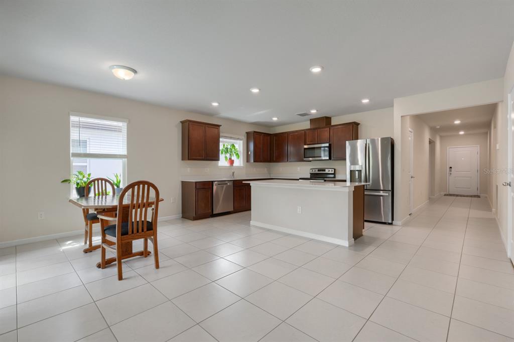 A kitchen with dark wood cabinets, stainless steel appliances, and a dining area with tile flooring — 30169 MERILEE PLACE, WESLEY CHAPEL, FL
