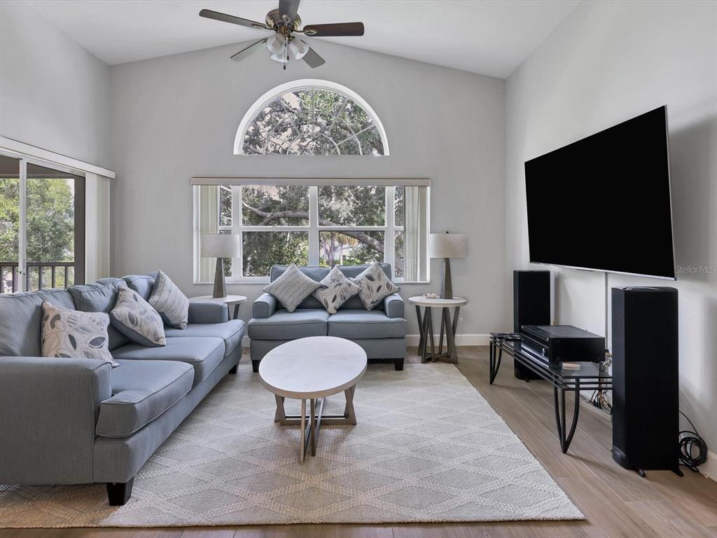 A living room features a blue sofa and loveseat, a coffee table, and a television — 7234 ELEANOR CIRCLE UNIT 203, SARASOTA, FL