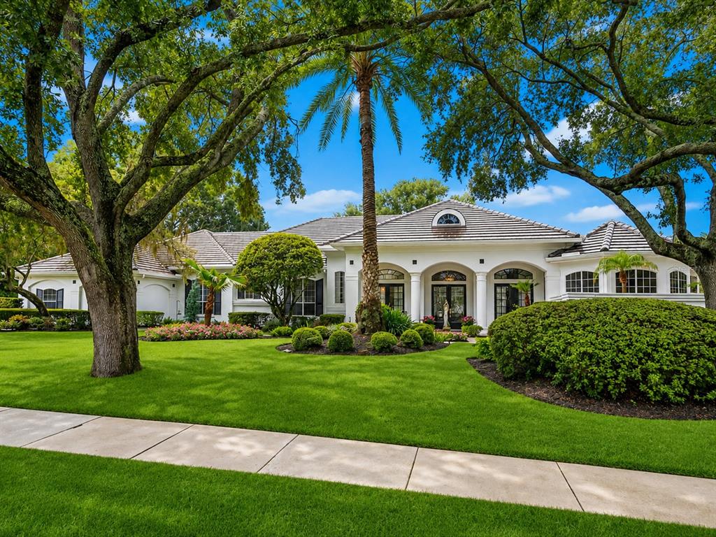 A white single-story house with a tile roof, arched entryway, and large front lawn — 9004 GREAT HERON CIRCLE, ORLANDO, FL