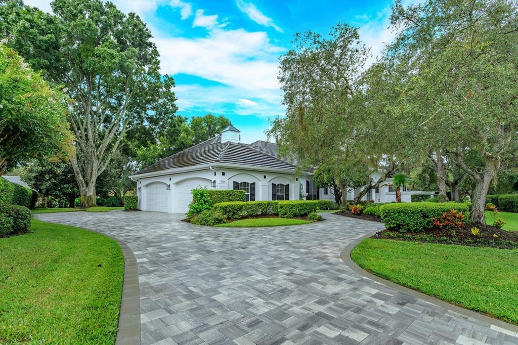 A white house with a tiled roof and a paved driveway surrounded by green landscaping — 9004 GREAT HERON CIRCLE, ORLANDO, FL