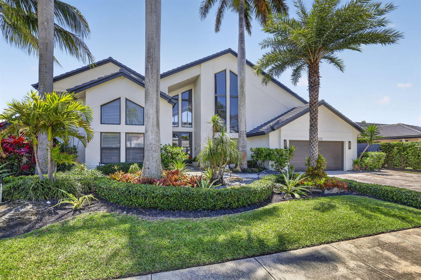A two-story house with a white exterior, dark roof, and palm trees in the yard — 2920 NE 47th Street, Lighthouse Point FL 33064, LIGHTHOUSE POINT, FL