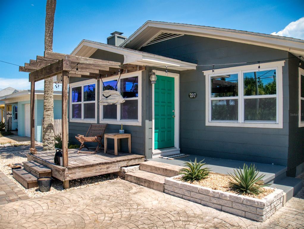 A gray house with a teal front door, a wooden pergola, and a stone planter — 207 Kirkland ROAD, NEW SMYRNA BEACH, FL