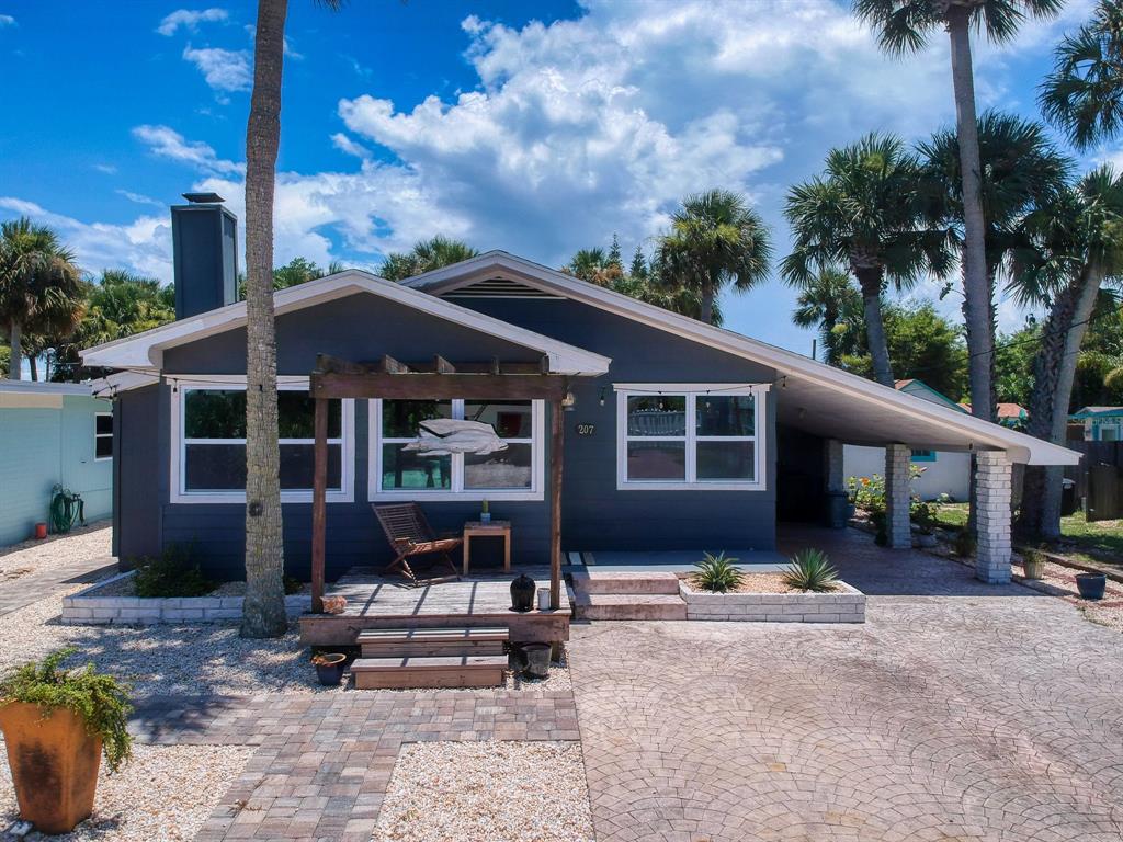 A dark gray single-story house features a wooden pergola, front deck, and a paved driveway — 207 Kirkland ROAD, NEW SMYRNA BEACH, FL