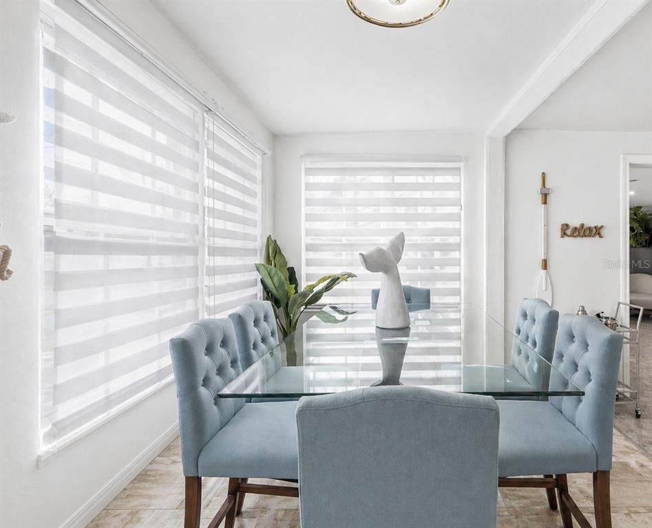 A dining room features a glass table, light blue tufted chairs, and striped window shades — 7799 46TH AVE N, ST PETERSBURG, FL