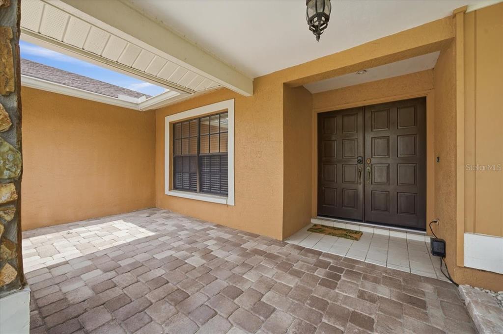 A covered entryway features a paver patio, a large window, and double front doors — 11803 SWEETPEA COURT, TAMPA, FL