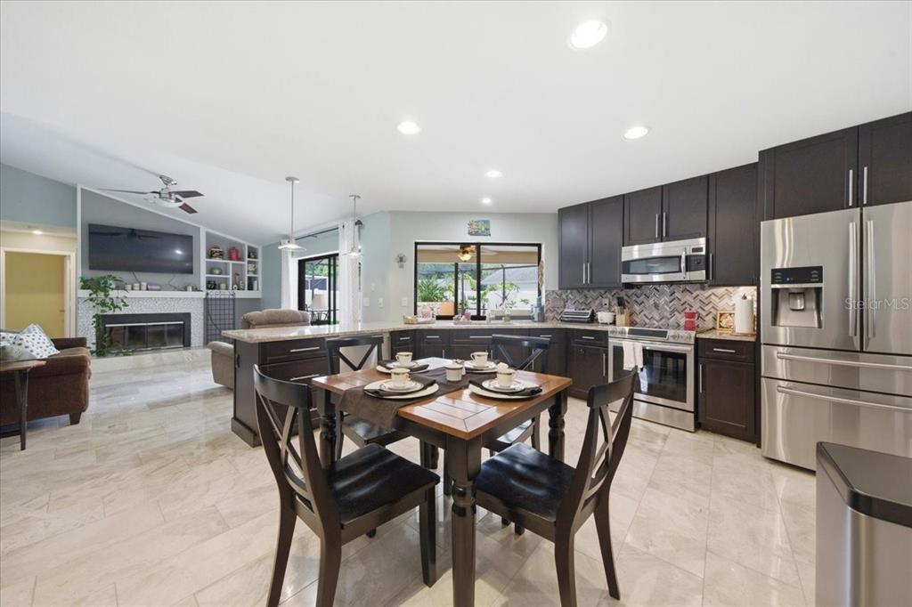 A kitchen with dark cabinets, stainless steel appliances, and a dining table on tile floors — 11803 SWEETPEA COURT, TAMPA, FL